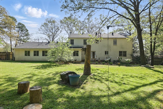 rear view of house with a yard, fence, and roof with shingles