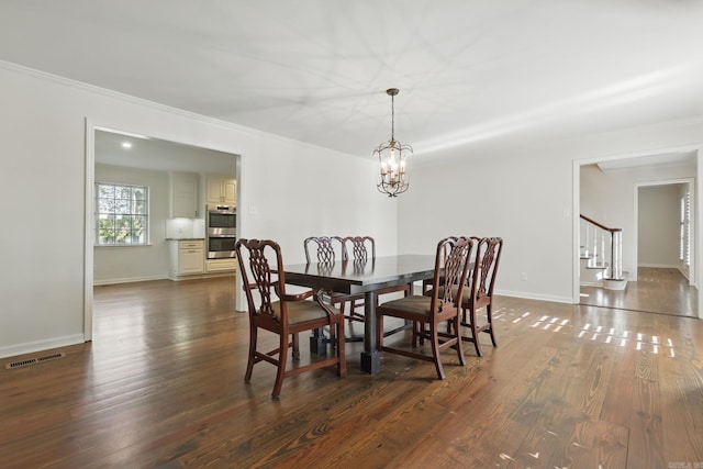 dining area with dark wood-type flooring, crown molding, an inviting chandelier, and stairs