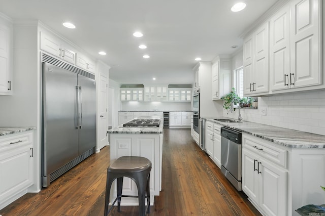 kitchen featuring stainless steel appliances, white cabinets, a sink, and a kitchen island