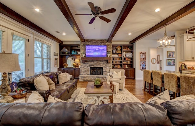 2136 Avondale, Benton, AR 72019 - living room with visible vents, a stone fireplace, beamed ceiling, wood finished floors, and ceiling fan with notable chandelier