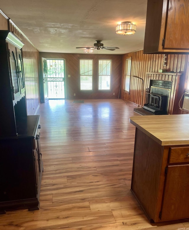 interior space featuring open floor plan, light wood finished floors, a ceiling fan, and a wood stove