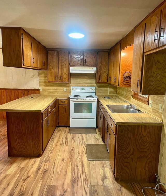 kitchen featuring a peninsula, light countertops, white electric stove, under cabinet range hood, and a sink