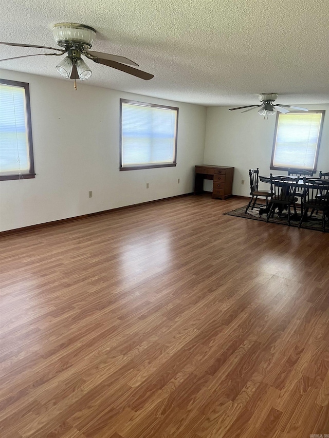 interior space with a textured ceiling, a ceiling fan, and wood finished floors