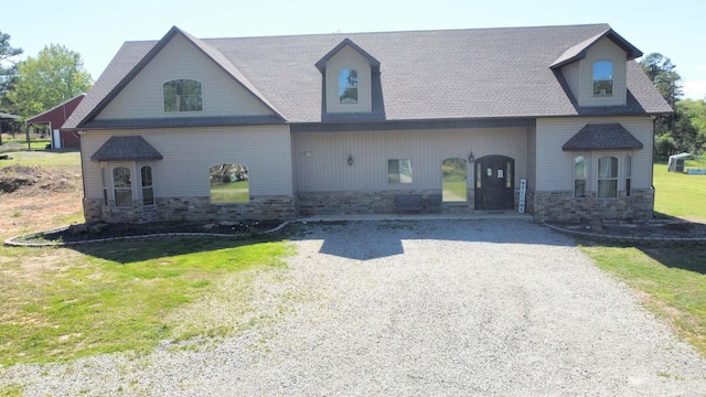 view of front facade featuring driveway, a front yard, and stone siding