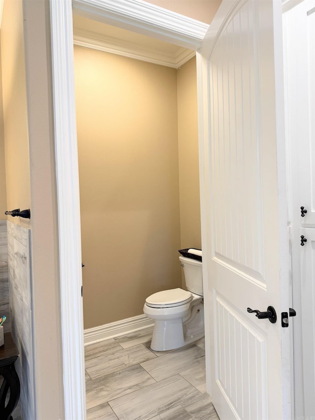 bathroom with crown molding, toilet, and baseboards