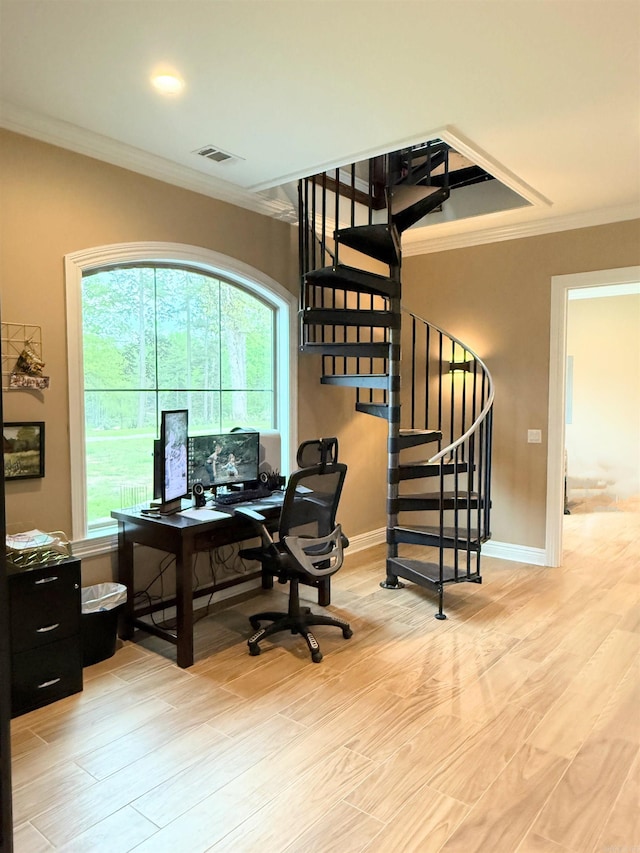 office space with baseboards, visible vents, light wood-type flooring, and crown molding