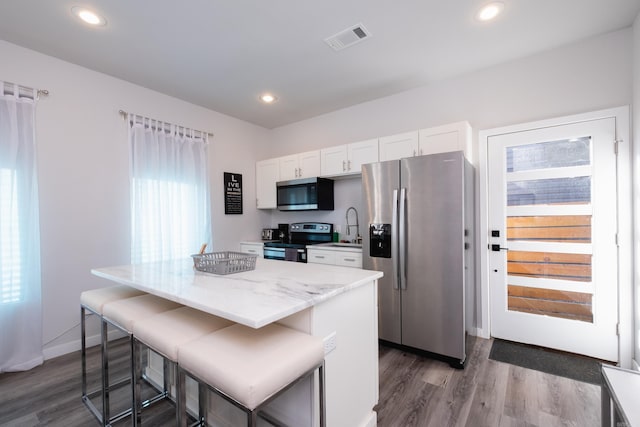 kitchen featuring stainless steel appliances, visible vents, a center island, and dark wood-style floors