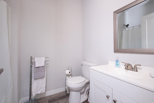 full bathroom with toilet, vanity, wood finished floors, and baseboards