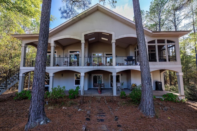 rear view of property with a patio, stairway, stucco siding, and a balcony