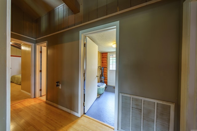 corridor featuring visible vents, baseboards, and wood finished floors