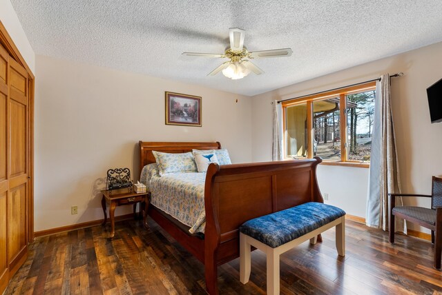 bedroom with dark wood-style floors, a textured ceiling, baseboards, and ceiling fan