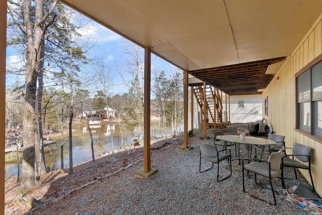 view of patio / terrace with a water view, outdoor dining space, and stairs