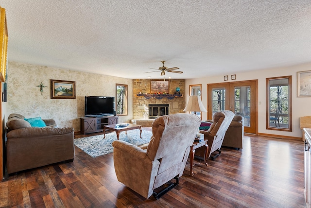 living area with dark wood-type flooring, a textured ceiling, a fireplace, and a ceiling fan