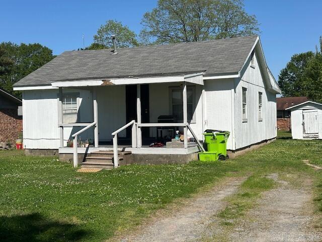bungalow-style home with a front yard, an outdoor structure, and a storage shed