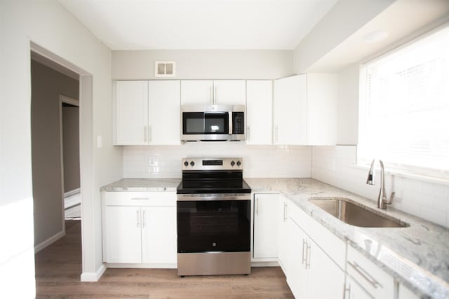 7204 W Wakefield Dr, Little Rock, AR 72209 - kitchen featuring light stone countertops, visible vents, appliances with stainless steel finishes, a sink, and light wood finished floors