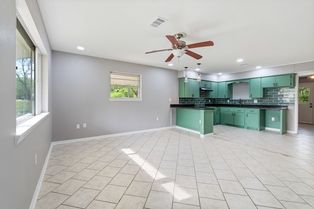 kitchen with dark countertops, a ceiling fan, a peninsula, green cabinets, and backsplash