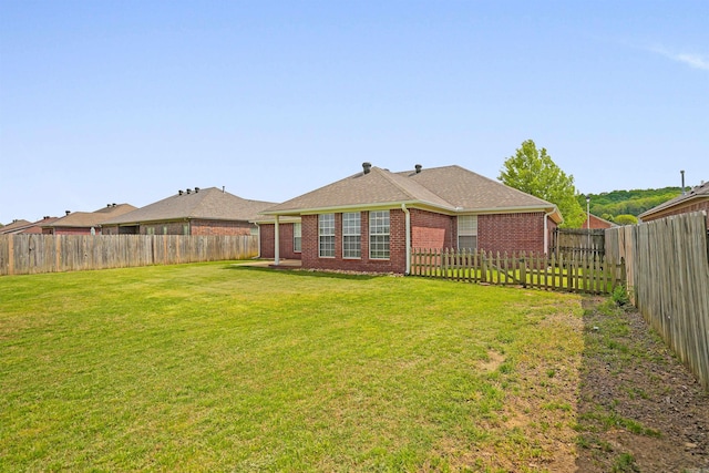 2540 Gladiola, Conway, AR 72034 - back of house featuring a shingled roof, a yard, a fenced backyard, and brick siding