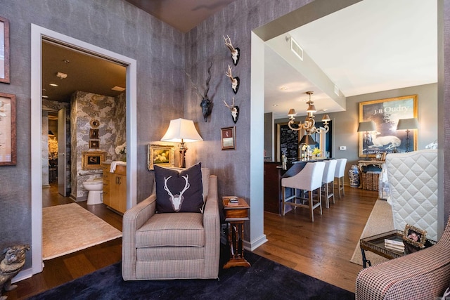 living area with visible vents, baseboards, a chandelier, and wood finished floors