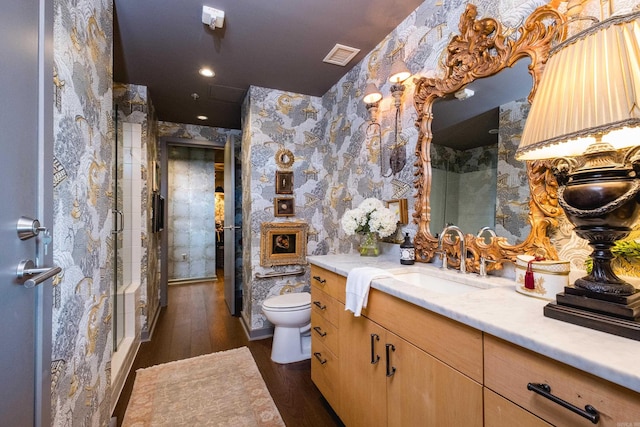 full bathroom with visible vents, toilet, vanity, wood finished floors, and wallpapered walls