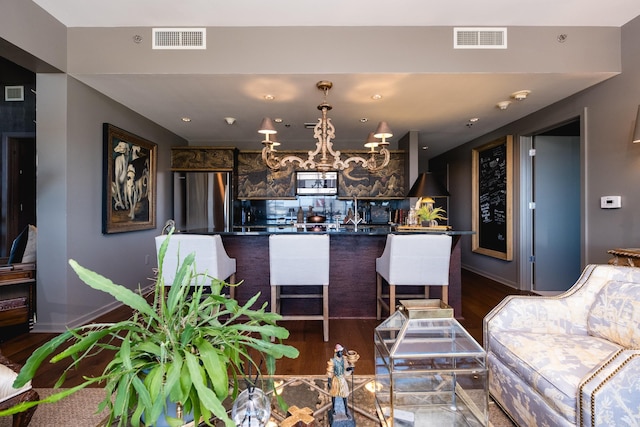 living room with a notable chandelier, dark wood-type flooring, visible vents, and baseboards