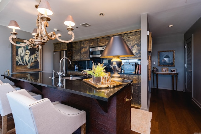 kitchen with a kitchen bar, dark wood-style flooring, a sink, and stainless steel appliances