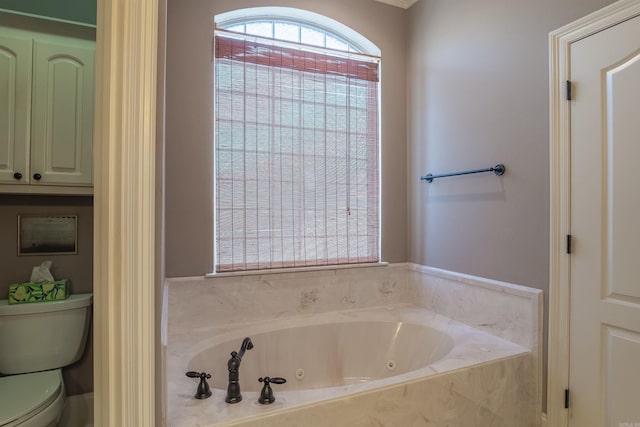 bathroom with toilet and a tub with jets