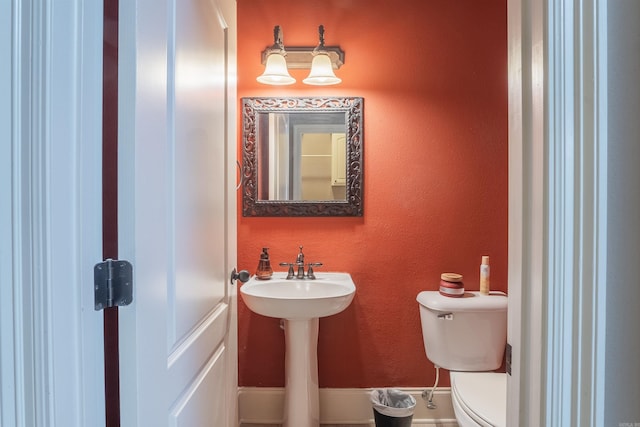 bathroom featuring toilet and a textured wall