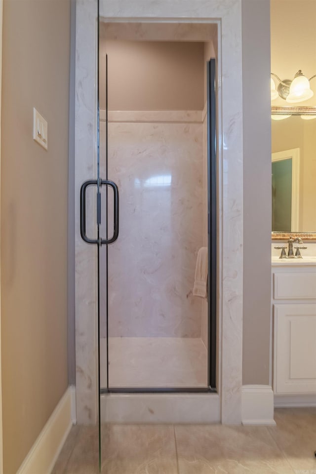 full bath with tile patterned floors, a marble finish shower, and vanity
