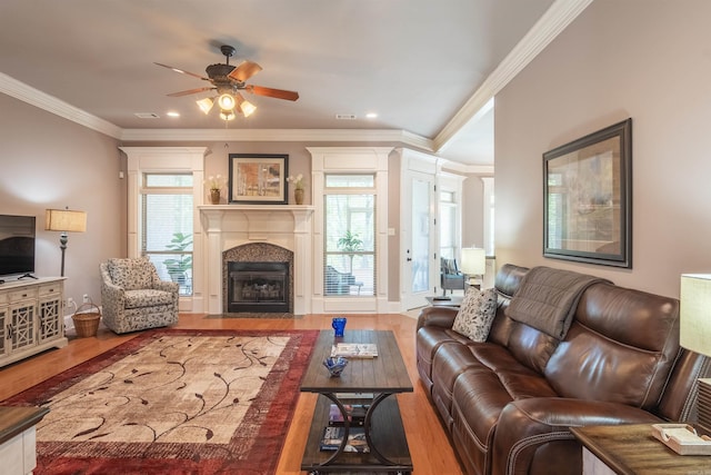 living room featuring ceiling fan, crown molding, recessed lighting, wood finished floors, and a fireplace with flush hearth
