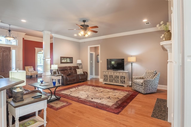living area with baseboards, a ceiling fan, crown molding, ornate columns, and wood finished floors