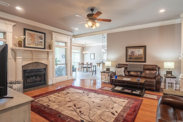 living area with ornamental molding, visible vents, a ceiling fan, and wood finished floors