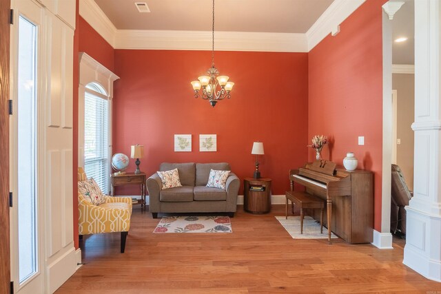 living room featuring an inviting chandelier, light wood finished floors, and crown molding