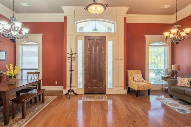 entryway featuring ornamental molding, baseboards, an inviting chandelier, and light wood-style floors