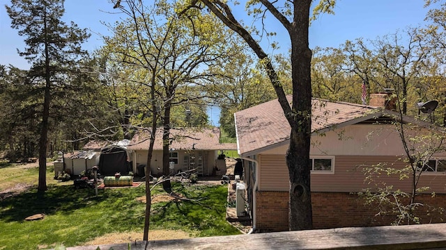 1012 Fairwater Cir, Horseshoe Bend, AR 72512 - exterior space with brick siding, a shingled roof, a yard, and a chimney