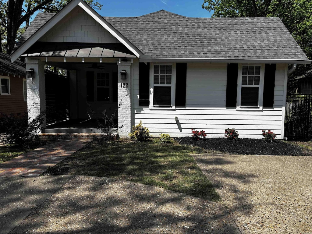 view of front facade with a carport, a standing seam roof, a shingled roof, and metal roof