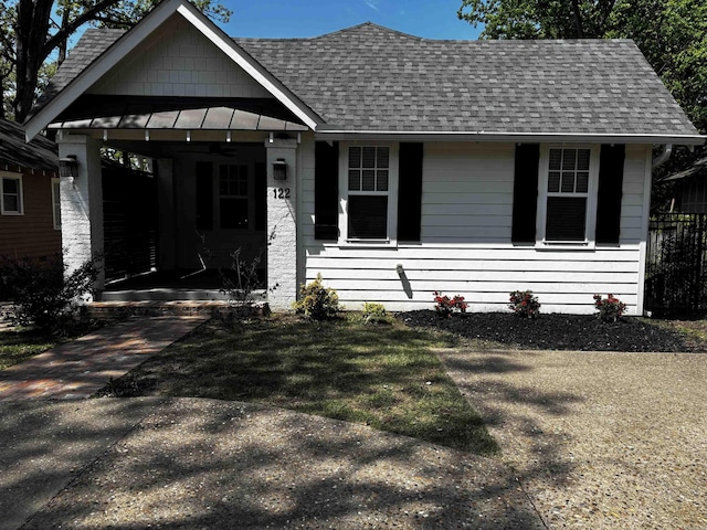 view of front facade with a carport, a standing seam roof, a shingled roof, and metal roof
