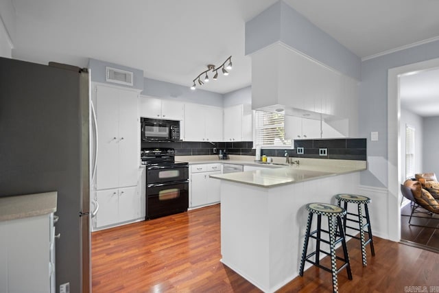 6808 Sandpiper Dr, Little Rock, AR 72205 - kitchen featuring dark wood finished floors, a peninsula, visible vents, black appliances, and a sink