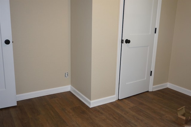 unfurnished bedroom with baseboards and dark wood-style floors