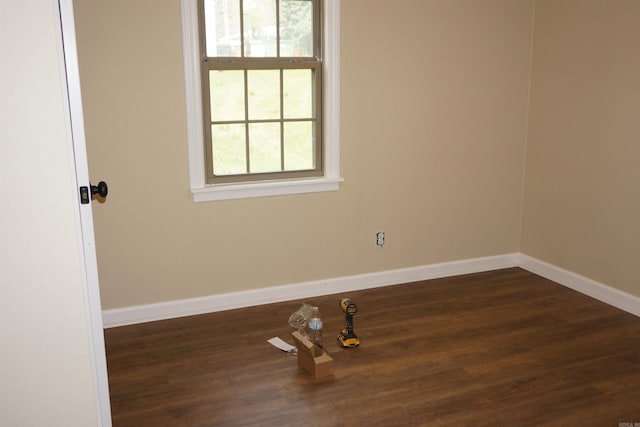 spare room with dark wood finished floors, baseboards, and plenty of natural light