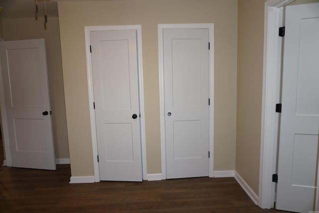 unfurnished bedroom featuring baseboards and dark wood-style flooring