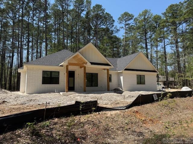 property in mid-construction featuring a patio area, brick siding, and a shingled roof