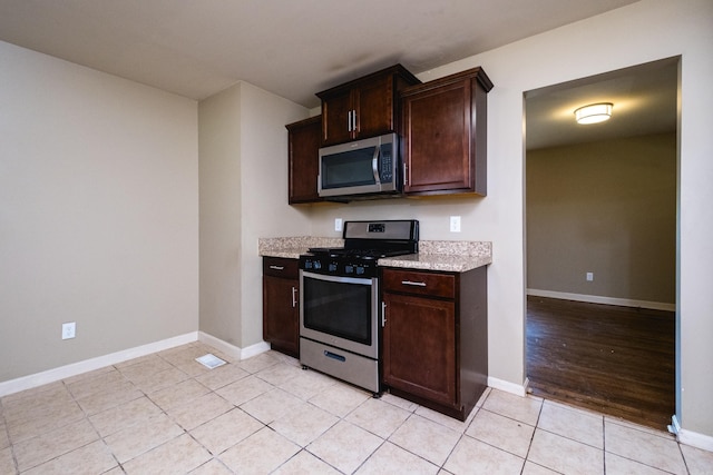 6 Broadmoor Dr, Little Rock, AR 72204 - kitchen featuring baseboards, dark brown cabinets, stainless steel appliances, light tile patterned flooring, and light stone counters