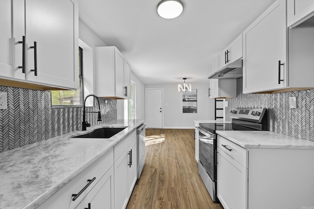 kitchen with white cabinets, under cabinet range hood, a sink, stainless steel appliances, and backsplash