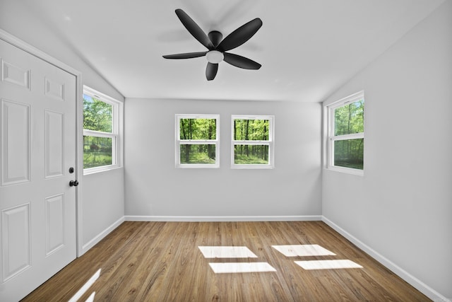 spare room with baseboards, wood finished floors, a ceiling fan, and lofted ceiling