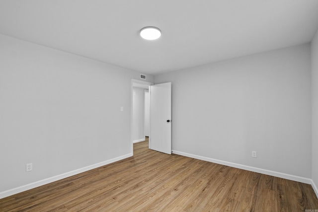 spare room featuring wood finished floors, baseboards, and visible vents