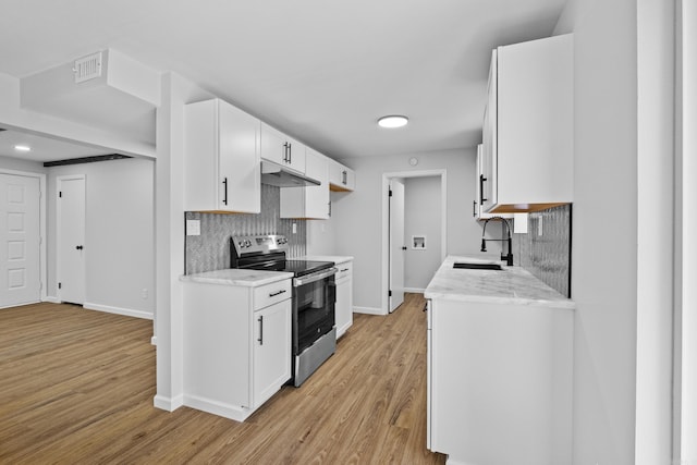 kitchen with backsplash, baseboards, a sink, and stainless steel range with electric cooktop