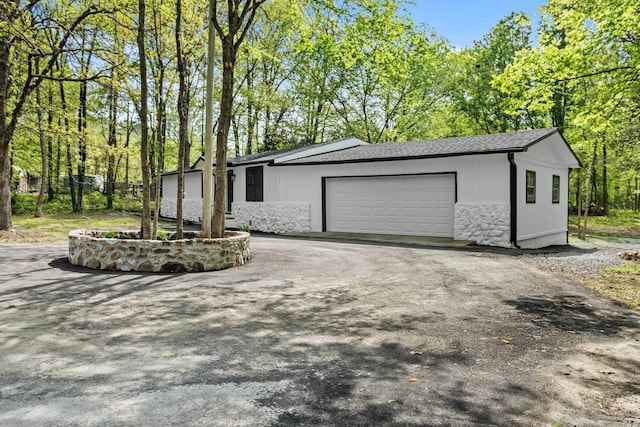 exterior space with roof with shingles, driveway, and a garage