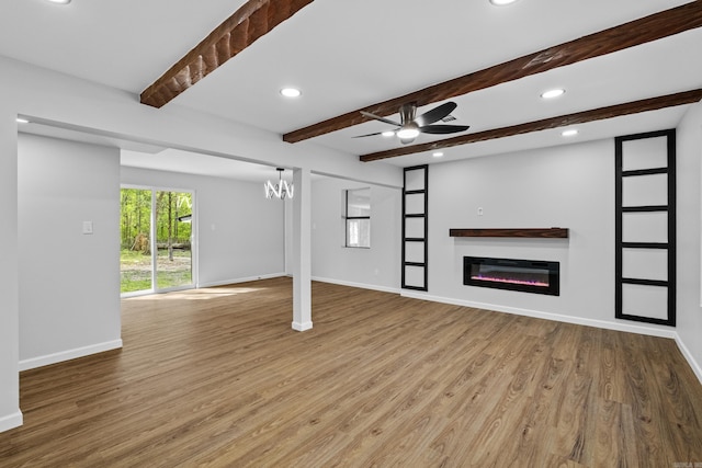 unfurnished living room with wood finished floors, baseboards, a glass covered fireplace, and recessed lighting