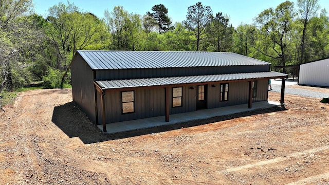 back of property with a porch, board and batten siding, and metal roof