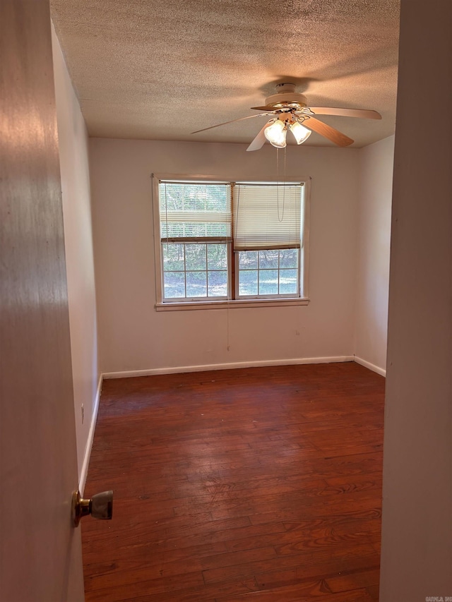 spare room featuring ceiling fan, dark wood-style floors, baseboards, and a textured ceiling